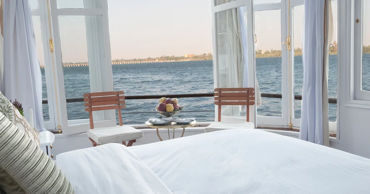 Luxurious suite interior on the Altesse Dahabiya with a panoramic river view.