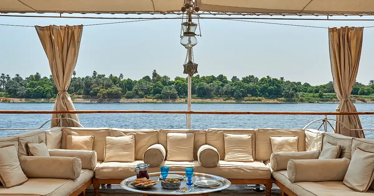 Elegant Roi Farouk Dahabiya sailing on the Nile with the Egyptian flag.