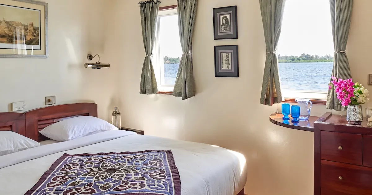Interior of a cabin on the Albatros Dahabiya with a large panoramic window view.