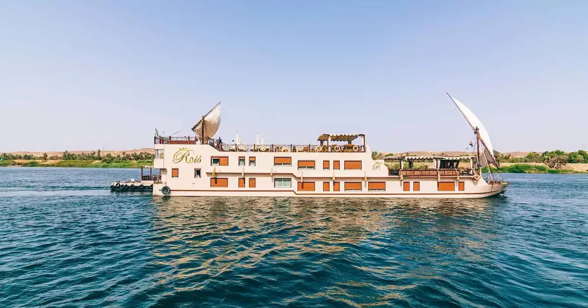 Elegant Roi Farouk Dahabiya sailing on the Nile with the Egyptian flag.