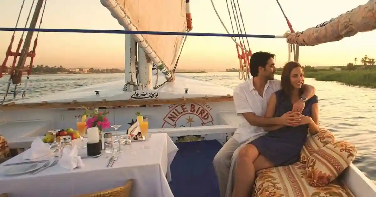 Couple on a felucca sailboat at sunset near Aswan